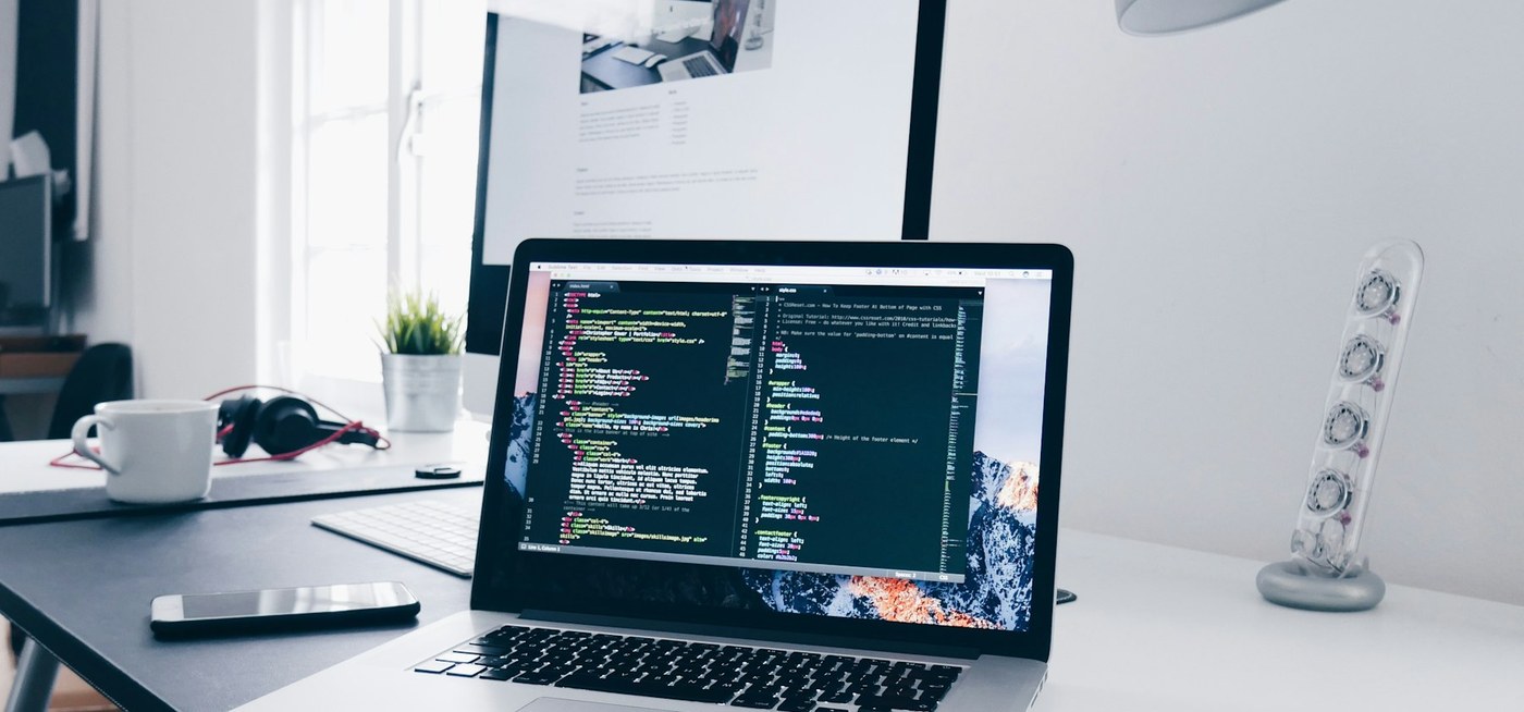 Ordinateur portable affichant du code source sur un bureau, symbole de maintenance applicative continue.